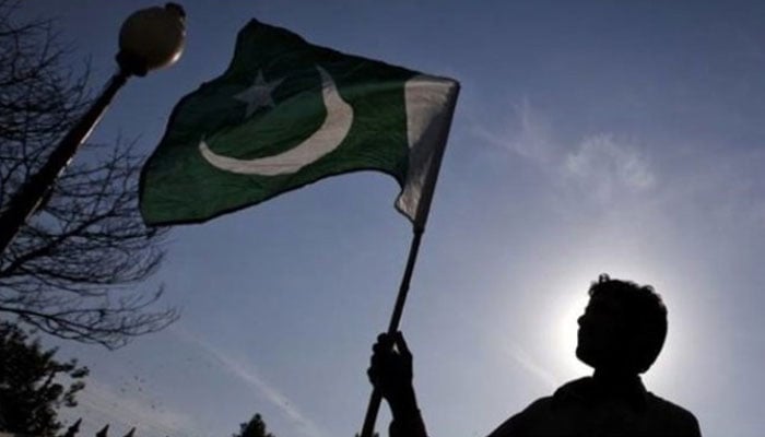 A man holds a flag of Pakistan. — Reuters