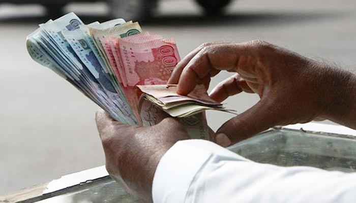 A currency dealer can be seen counting Pakistani notes