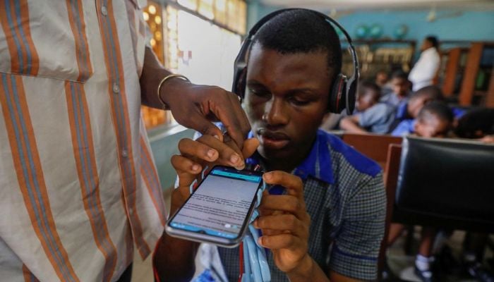 A Vinsighte team member assists a visually impaired student with the Visis app, which aims at helping him read, at Pacelli School for the Blind and Partially Sighted Children, in Lagos, Nigeria, October 12, 2022.— Reuters