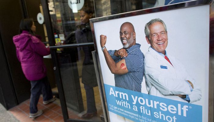 People enter a pharmacy next to a sign promoting flu shots in New York January 10, 2013.— Reuters