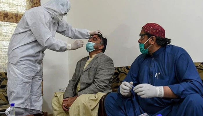 A health worker takes a testing sample from a journalist during a nationwide lockdown over the Covid-19 pandemic in Pakistan. — AFP