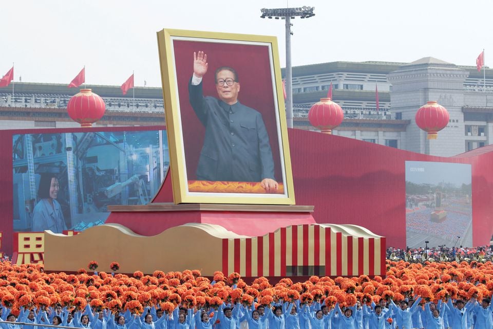 1 اکتوبر 2019 کو بیجنگ، چین میں اس کے قومی دن کے موقع پر عوامی جمہوریہ چین کی 70 ویں یوم تاسیس کے موقع پر پریڈ کے دوران سابق چینی صدر جیانگ زیمن کو دکھائے جانے والے فلوٹ کے ساتھ کام کرنے والے تیانمن اسکوائر سے گزر رہے ہیں۔— رائٹرز