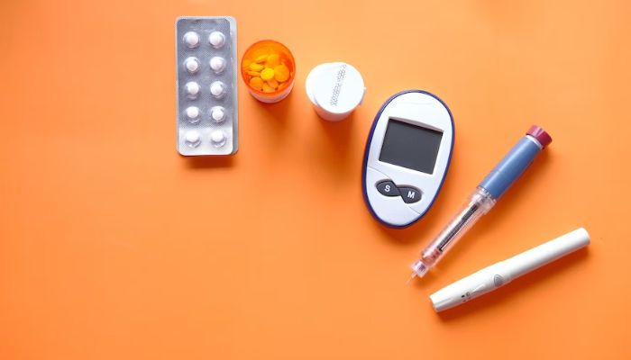 An insulin pen, diabetic measurement tools and pills on orange background.— Unsplash