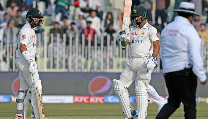 Pakistans Abdullah Shafique (2R) celebrates after scoring half century (50 runs) as teammate Imam-ul-Haq (L) watches during the second day of the first cricket Test match between Pakistan and England at the Rawalpindi Cricket Stadium, in Rawalpindi on December 2, 2022. — AFP