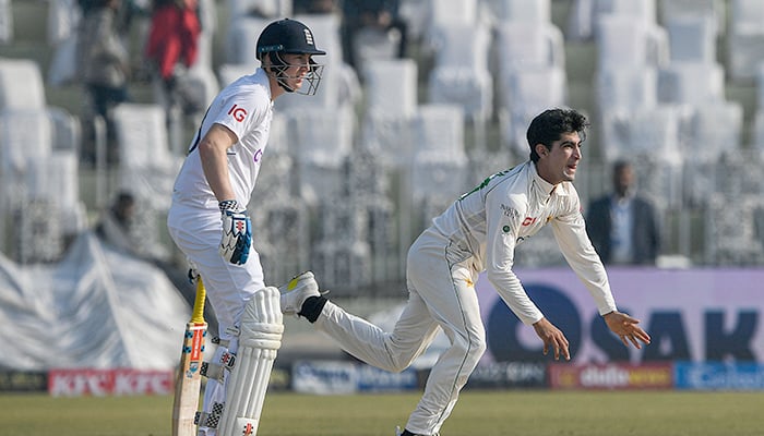 Pakistans Naseem Shah (R) delivers the ball next to Englands Harry Brook during the second day of the first cricket Test match between Pakistan and England at the Rawalpindi Cricket Stadium, in Rawalpindi on December 2, 2022. — AFP