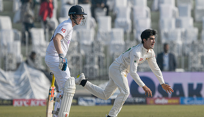 Pakistans Naseem Shah (R) delivers the ball next to Englands Harry Brook during the second day of the first cricket Test match between Pakistan and England at the Rawalpindi Cricket Stadium, in Rawalpindi on December 2, 2022. — AFP