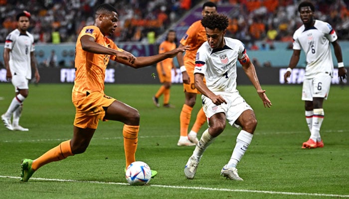 Netherlands defender #22 Denzel Dumfries (L) fights for the ball with USAs midfielder #04 Tyler Adams during the Qatar 2022 World Cup round of 16 football match between the Netherlands and USA at Khalifa International Stadium in Doha on December 3, 2022.— AFP