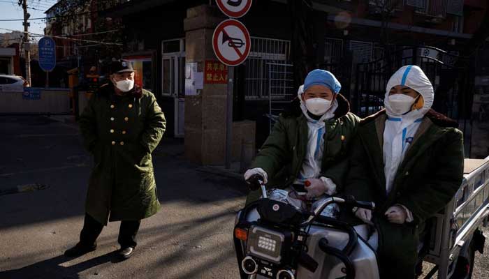 Pandemic prevention workers in protective suits ride an electric vehicle as coronavirus disease (COVID-19) outbreaks continue in Beijing, December 4, 2022. — Reuters