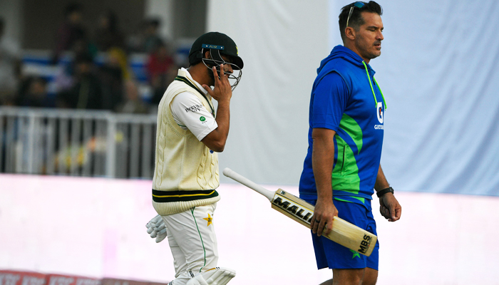 Pakistans Azhar Ali (L) back to pavilion after an injury during the fourth day of the first cricket Test match between Pakistan and England at the Rawalpindi Cricket Stadium, in Rawalpindi on December 4, 2022. -AFP