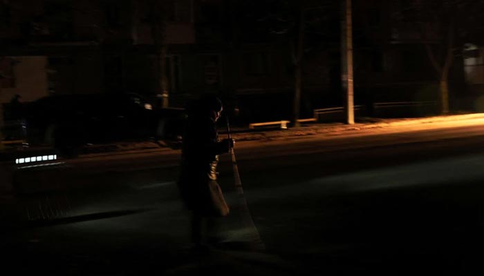 A woman uses a walking stick as she walks down a pitch black street during a blackout as Russias attack on Ukraine continues in Kramatorsk, Ukraine, November 24, 2022. — Reuters