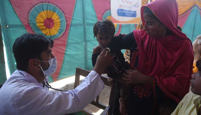 A Pakistani paramedic checks a child at a makeshift medical camp set in Dadu district, Sindh province on September 27, 2022. — AFP