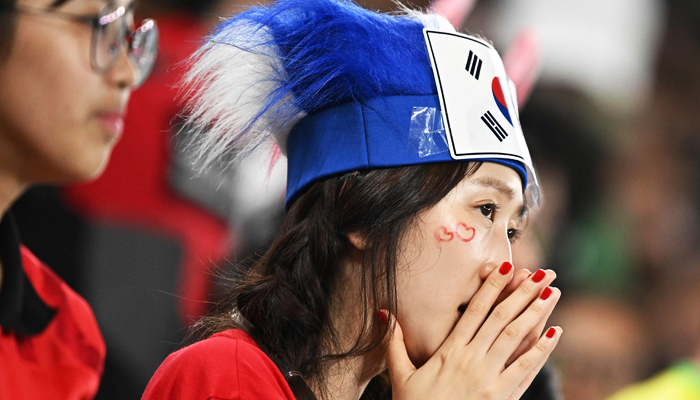 A South Korea supporter looks dejected after her team lost the Qatar 2022 World Cup round of 16 football match between Brazil and South Korea at Stadium 974 in Doha on December 5, 2022. -AFP