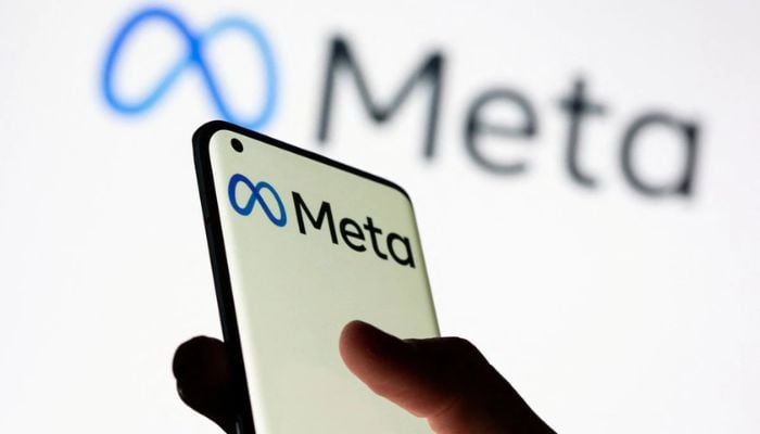 Woman holds smartphone with Meta logo in front of a displayed Facebooks new rebrand logo Meta in this illustration picture taken October 28, 2021.— Reuters