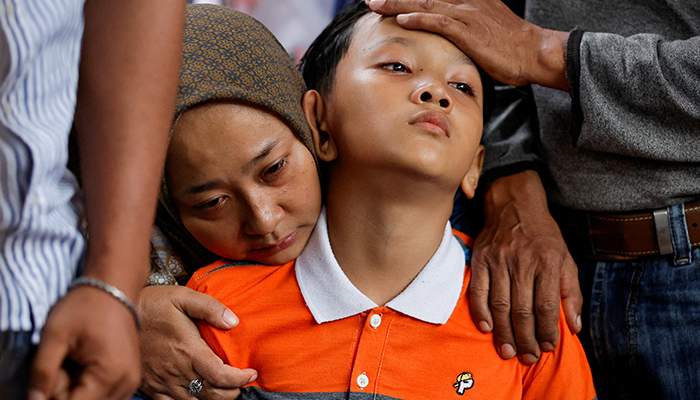 Siti Sarah and Al Fikri Ibnu Sofyan, wife and the third son of Agus Sofyan, a police officer who was killed in a blast at a district police station, that according to authorities was a suspected suicide bombing, mourn during the funeral in Bandung, West Java province, Indonesia, December 7, 2022. — Reuters