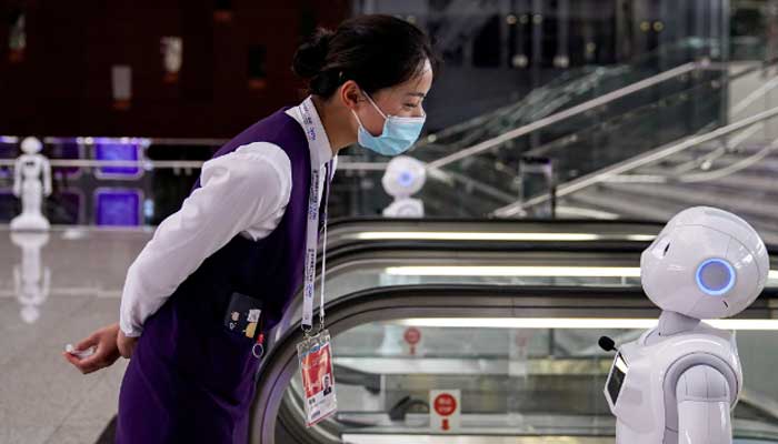 A staff member, wearing a face mask following the COVID-19 outbreak, looks at a robot at the venue for the World Artificial Intelligence Conference in Shanghai, China July 9, 2020. — Reuters