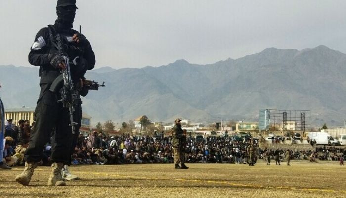 A Taliban security personnel stands guard as people attend to watch publicly flogging of women and men at a football stadium in Charikar city of Parwan province on December 8, 2022.— AFP