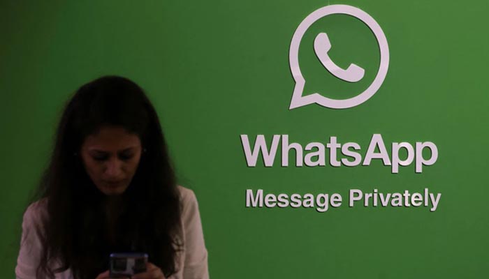A woman uses her phone next to a logo of the WhatsApp application during Global Fintech Fest in Mumbai, India September 20, 2022. — Reuters