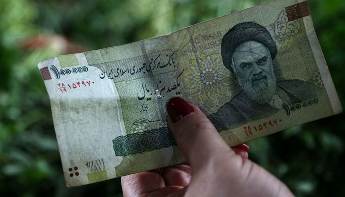 A woman holds an Iranian currency in Tajrish Bazaar in Tehran, Iran August 1, 2019. Nazanin Tabatabaee/WANA