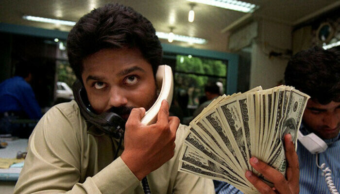 A money dealer talks on the phone while holding a fan of $100 banknotes. — AFP/File