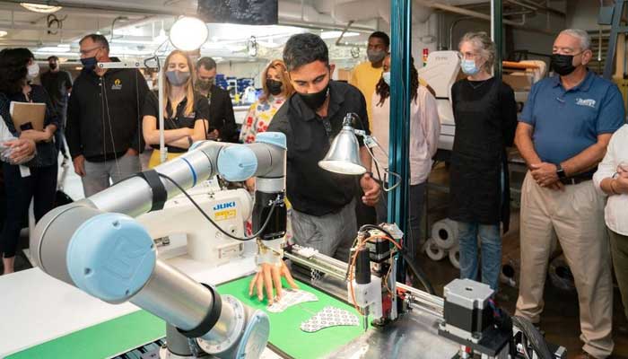 Siemens automation researcher Gokul Sathya Narayanan positions pieces of stiffened fabric for a Sewbo demonstration of robotic mask manufacturing at the Industrial Sewing and Innovation Center in Detroit, Michigan, U.S. August 19, 2021. — Reuters