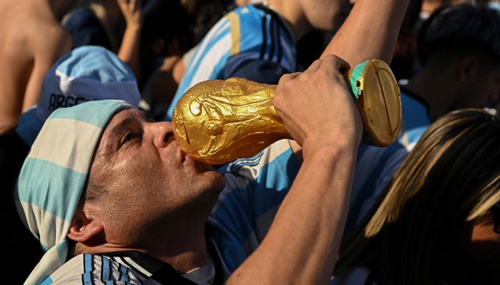 A fan of Argentina kisses a replica of the World Cup trophy as he celebrates his team´s victory after the Qatar 2022 World Cup semifinal football match between Croatia and Argentina at the Obelisk in Buenos Aires on December 13, 2022. — AFP