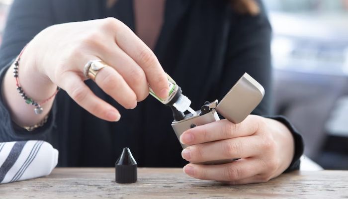 A woman refilling pod vape.— Unsplash