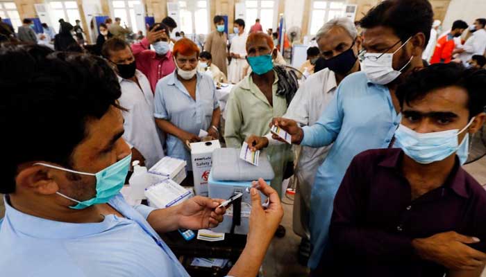 Residents with their registration cards gather at a counter to receive the coronavirus disease (COVID-19) vaccination at a vaccination center in Karachi, Pakistan, on June 9, 2021.  — Reuters