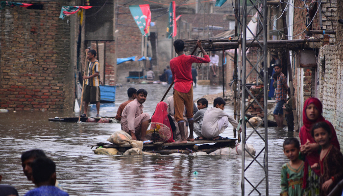 Residents use a raft to move along a waterlogged street in a residential area after a heavy monsoon rainfall in Hyderabad City on August 19, 2022. — AFP