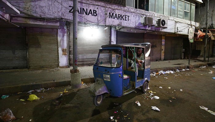 A view of a rickshaw driver standing near a closed market in Karachi on June 17, 2022. — INP/File