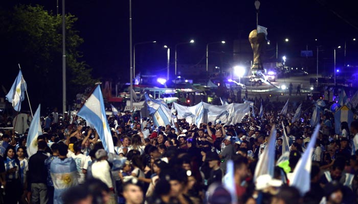Pendukung Argentina merayakan ketika mereka menunggu tim Argentina tiba di pusat pelatihan Asosiasi Sepak Bola Argentina (AFA) setelah memenangkan turnamen Piala Dunia Qatar 2022 di Ezeiza, provinsi Buenos Aires, Argentina pada 20 Desember 2022. — AFP