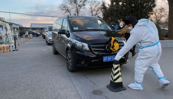 A worker in a protective suit removes a cone in front of a hearse outside funeral home, amid the coronavirus disease (COVID-19) outbreak in Beijing, China December 17, 2022.— Reuters