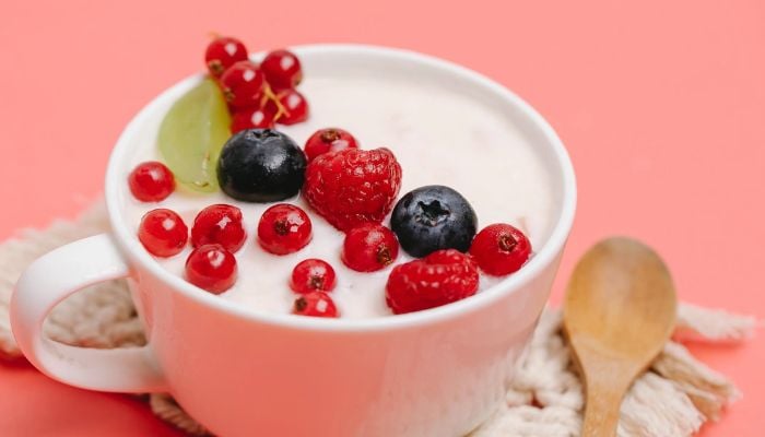 Tasty and healthy yoghurt with berries served on pink table with wooden spoon.— Pexels