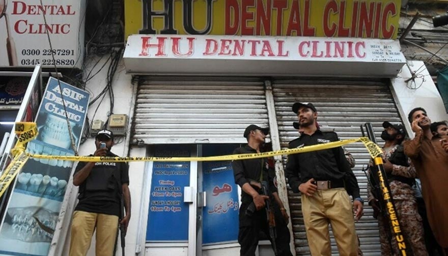 Policemen gather outside a dental clinic after a Chinese origin man was shot dead in an attack in Karachi on September 28, 2022. — AFP