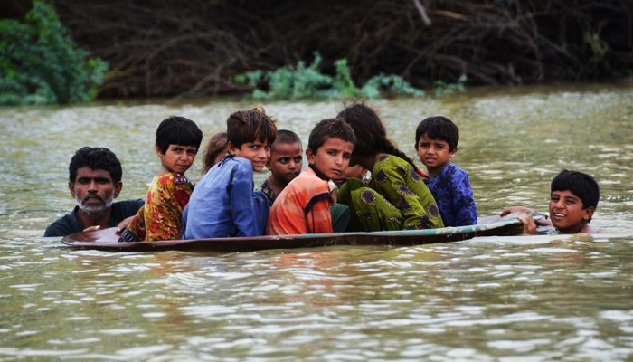 A man (left) and a youth (right) use a satellite dish to move children across a flooded area after heavy monsoon rainfalls in Jaffarabad District of Balochistan on August 26, 2022. — AFP