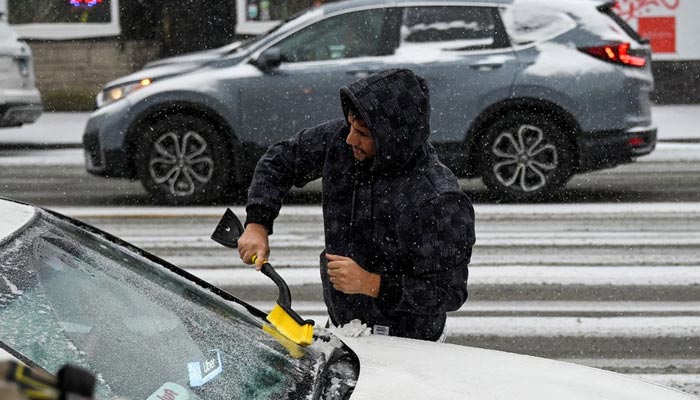 22 دسمبر، 2022 کو شکاگو، الینوائے، یو ایس میں، ایک ڈرائیور سرد موسم کے محاذ کے دوران اپنی کار سے برف کو کھرچ رہا ہے جب کہ بم سائیکلون کے نام سے جانا جاتا موسمی رجحان بالائی مڈویسٹ سے ٹکرایا۔