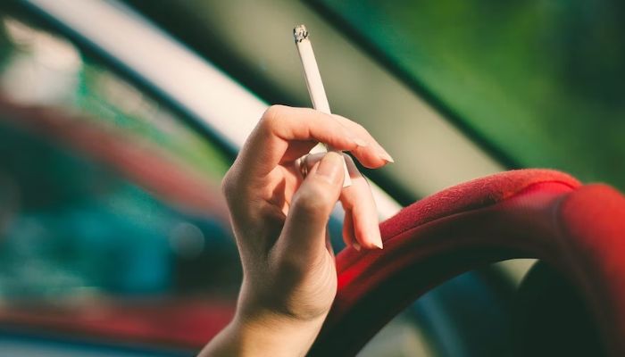A woman smoking a cigarette in the car.— Unsplash