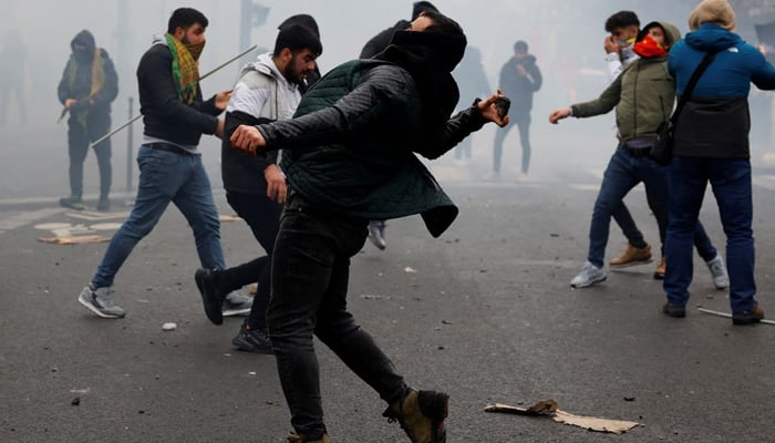 A person throws a projectile, as members of the Kurdish community attend a demonstration, REUTERS