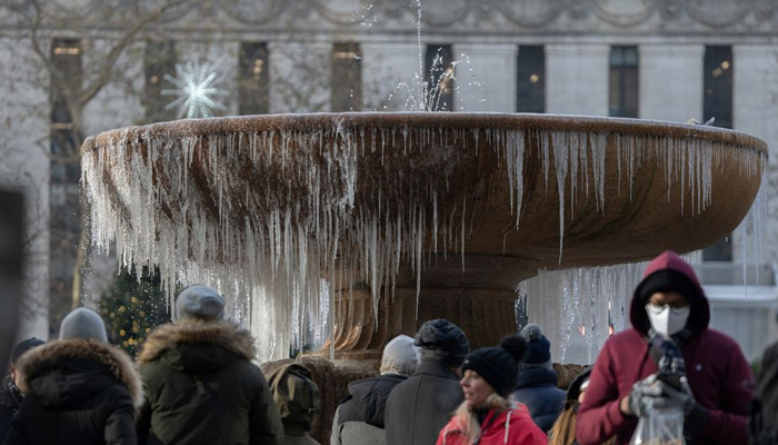 People stand in front of a mostly frozen Bryant Park fountain on Christmas Eve — REUTERS