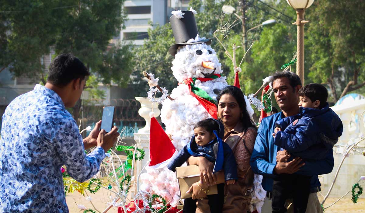 A family poses with an artificial snowman placed in the backdrop within the churchs grounds.