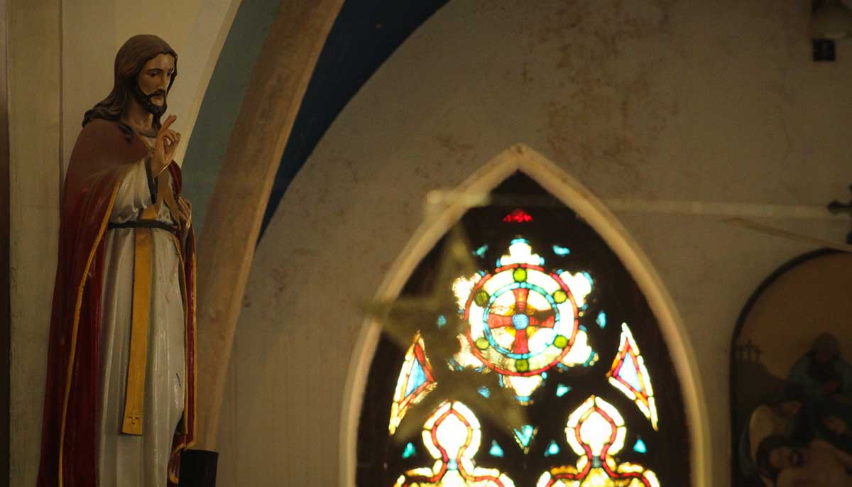 A figure of Jesus Christ looks on as windows of the two-century-old cathedral reflect sunlight.