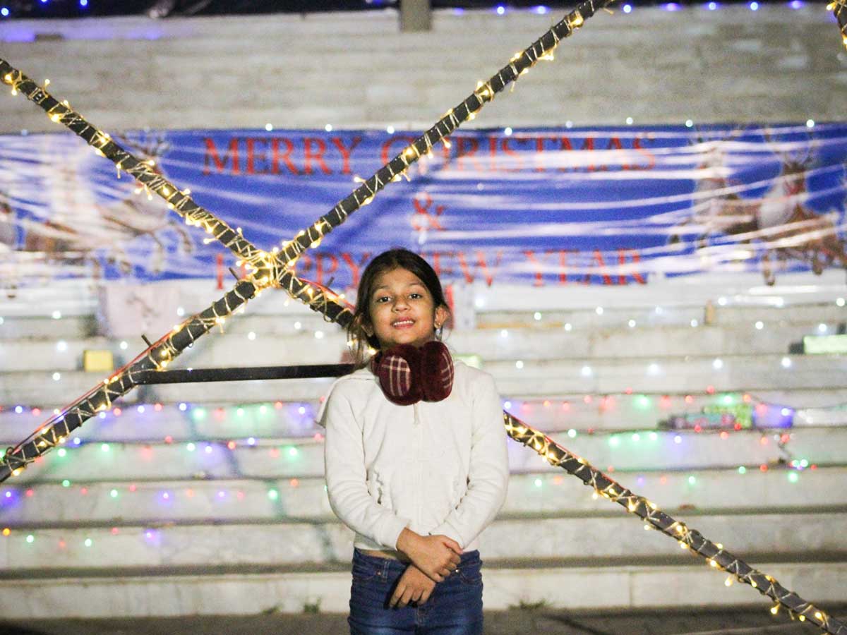 علینا نامی ایک چھوٹی لڑکی کرسمس کے موقع پر آدھی رات کے اجتماع سے پہلے تصویر کے لیے پوز دیتی ہے۔