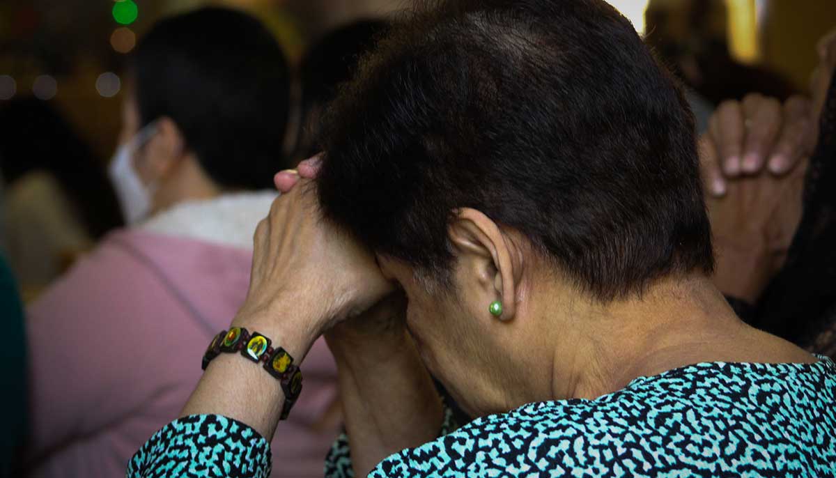 An elderly female devotee prays while the holy days congregational prayers take place.