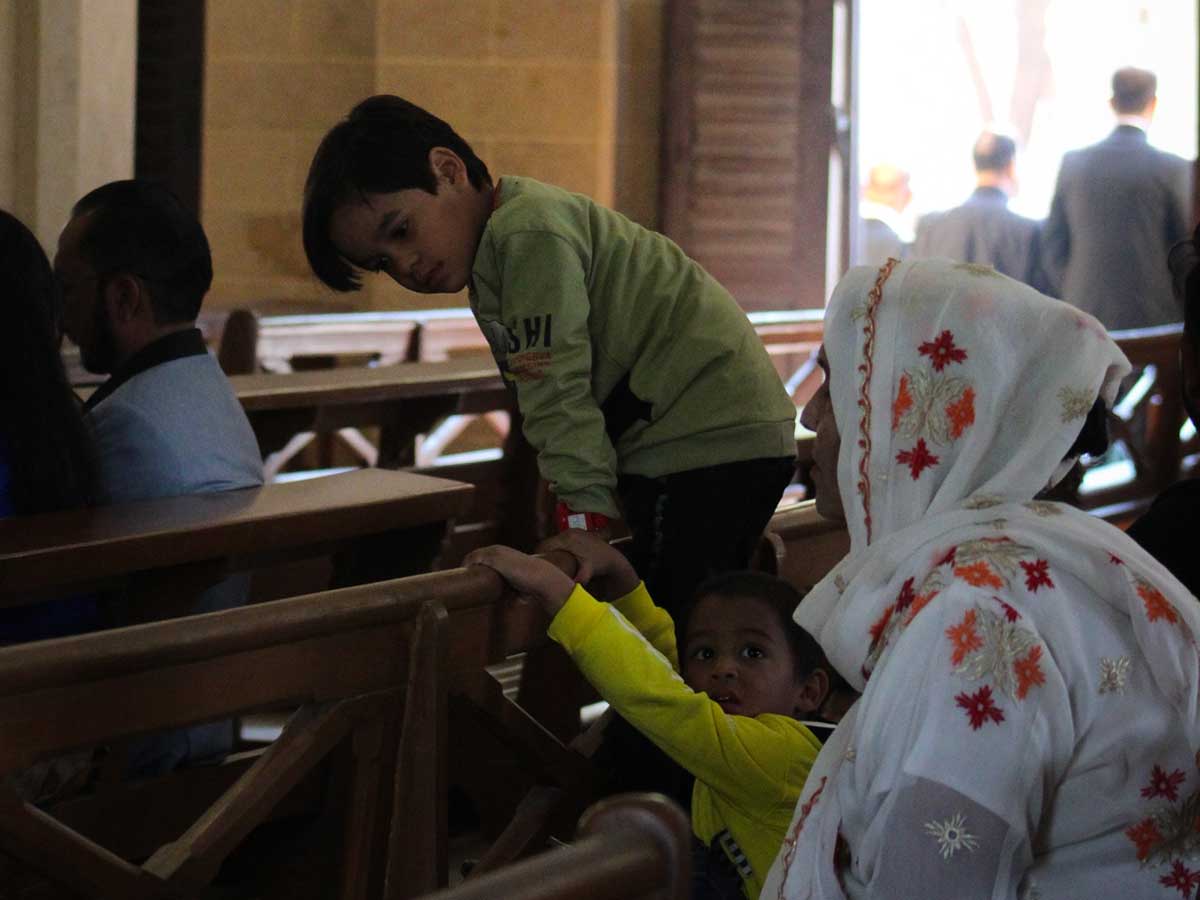 Children jump over pew chairs as their mother listens to the priests Christmas Day sermon.