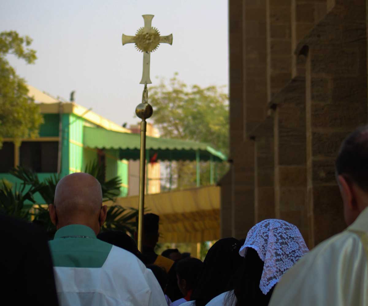 A group of devotees carry the processional crucifix as the Christmas Day mass approaches its end.