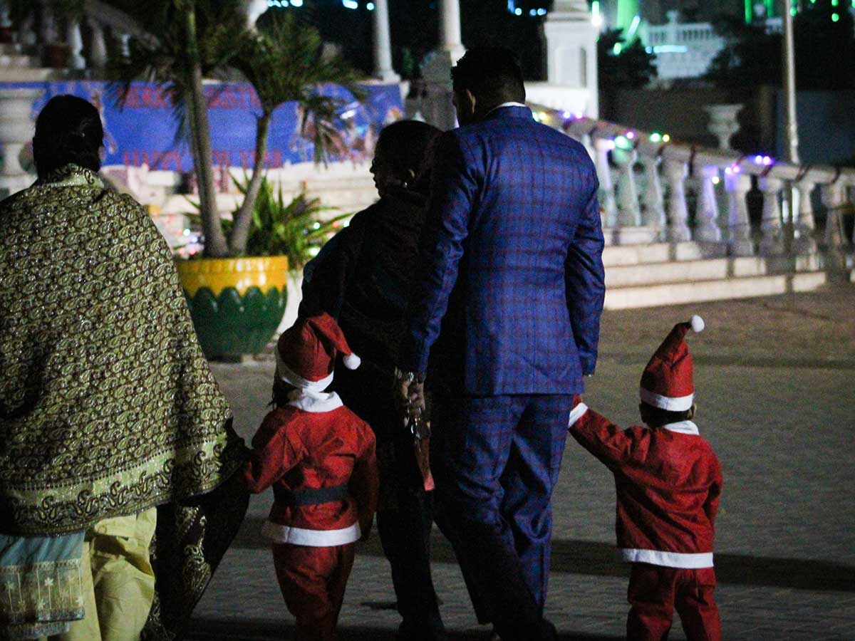 Two children dressed as Santa Claus walk towards the church to offer midnight mass on Christmas Eve.