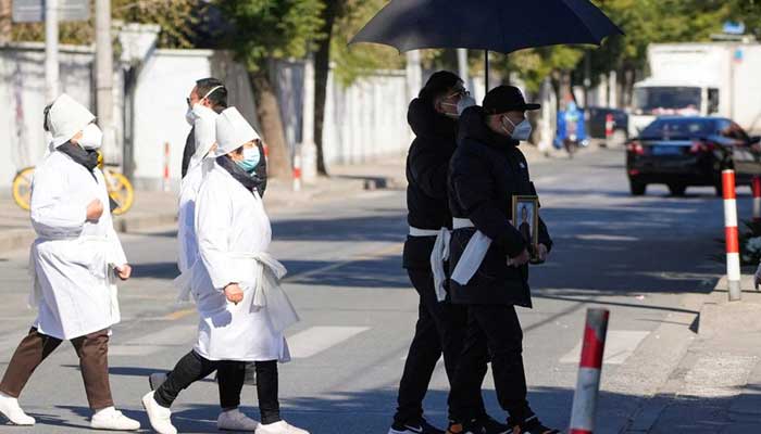 A man wearing a protective mask holds a picture frame of a loved one outside a funeral home in Shanghai, December 23, 2022. — Reuters