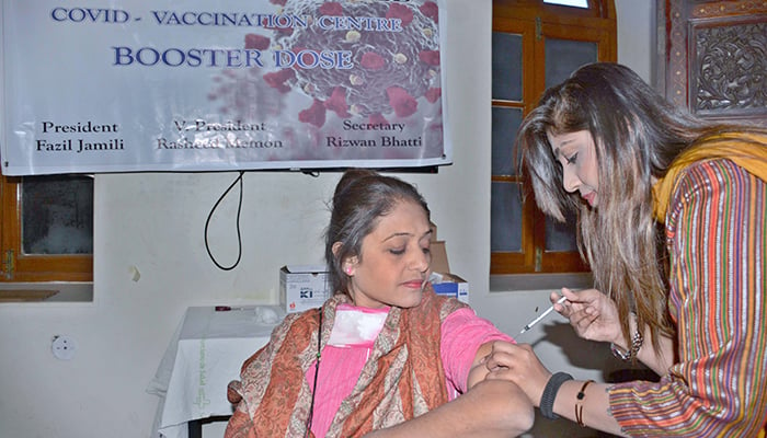 A female health worker administers a coronavirus booster vaccine injection to a woman at the Karachi Press Club on January 17, 2022. — APP