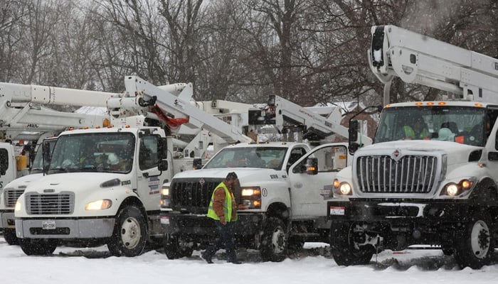 A utility worker walks by a truck in a staging area during a winter storm that hit the Buffalo region in Amherst, New York, US, December 26, 2022 — Reuters