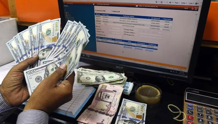 A money dealer counts $100 banknotes. —AFP/File
