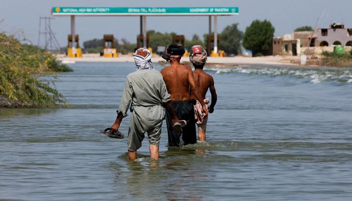 Displaced people walk on flooded highway, following rains and floods during the monsoon season in Sehwan, Pakistan, September 16, 2022. — Reuters